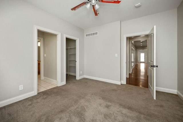 unfurnished bedroom with a ceiling fan, baseboards, visible vents, and carpet flooring