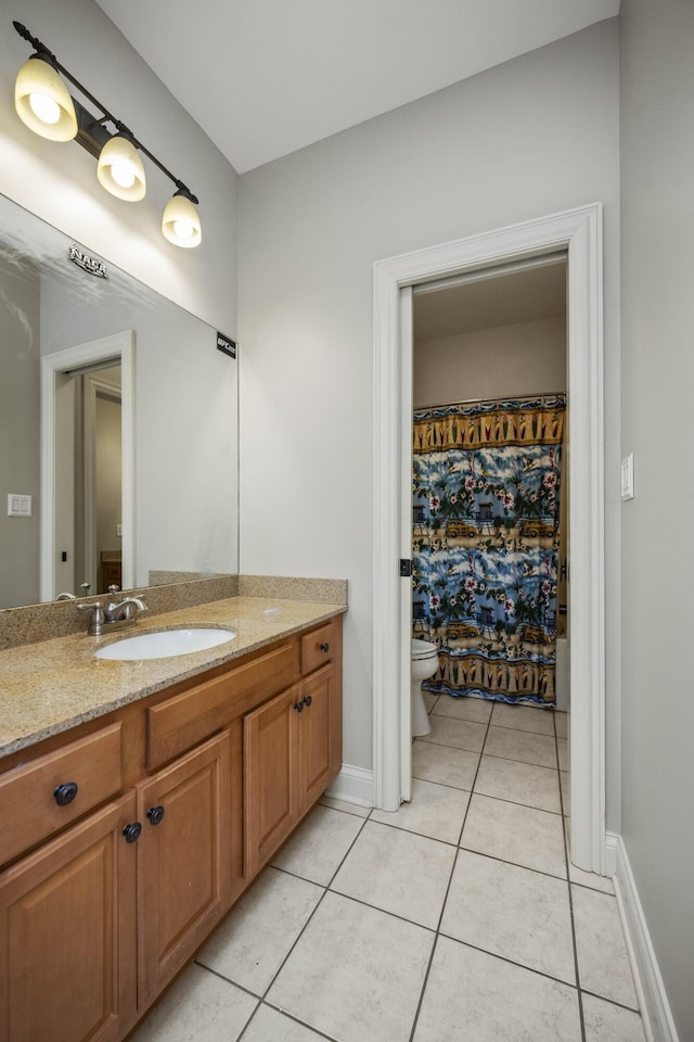 bathroom featuring tile patterned flooring, baseboards, vanity, and toilet