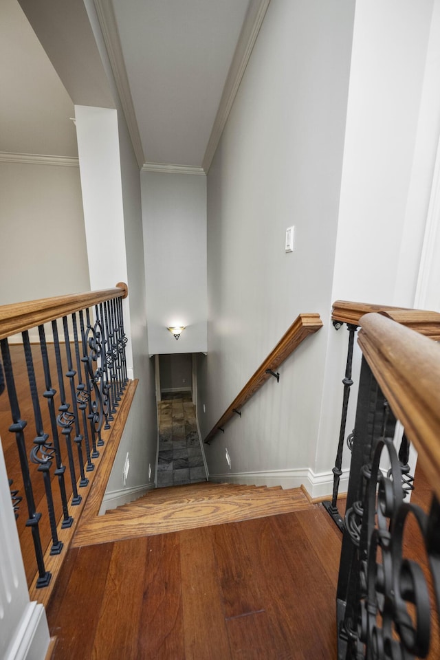 stairs with crown molding, baseboards, and wood finished floors