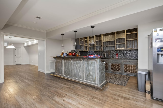 bar featuring visible vents, stainless steel fridge, backsplash, and wood finished floors