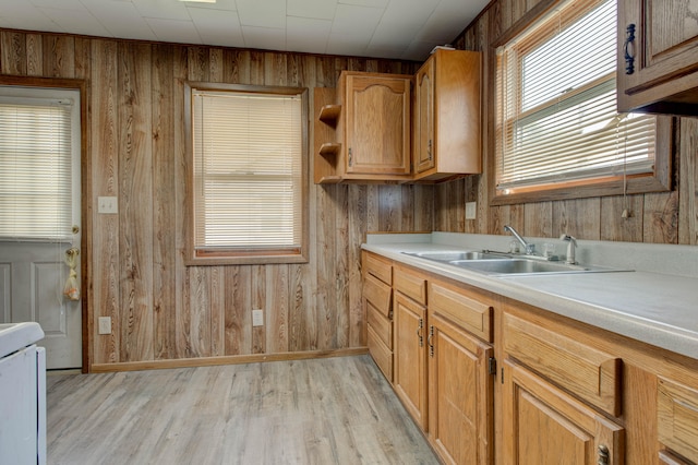 kitchen with sink, light wood-type flooring, and wooden walls