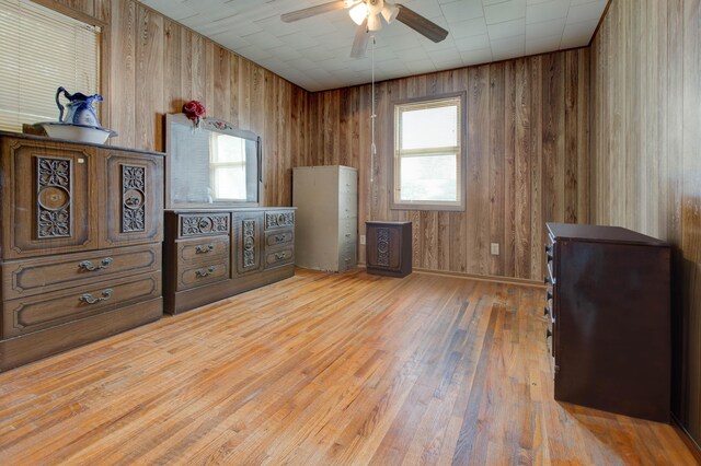 bedroom with hardwood / wood-style flooring, wood walls, and ceiling fan