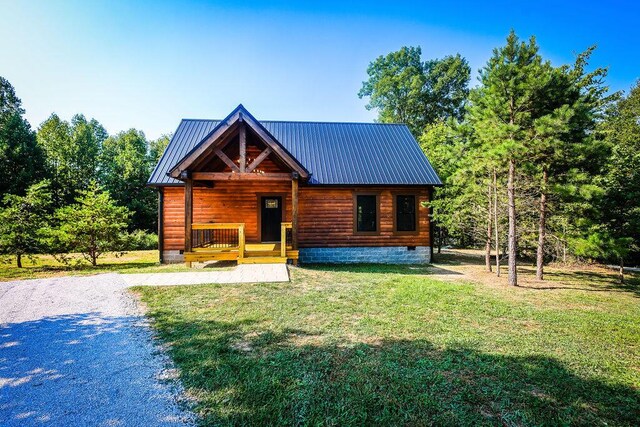 log cabin with covered porch and a front lawn