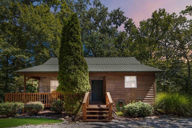 view of front of property with a porch, stone siding, and metal roof