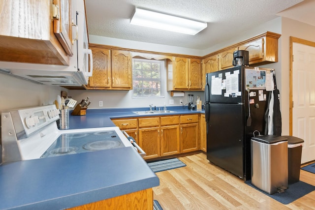 kitchen with freestanding refrigerator, light wood-style floors, brown cabinetry, white electric stove, and a sink