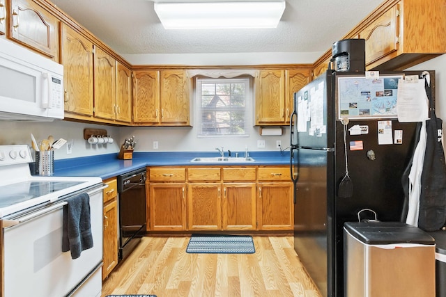 kitchen featuring black appliances, light wood-style flooring, a sink, a textured ceiling, and brown cabinetry