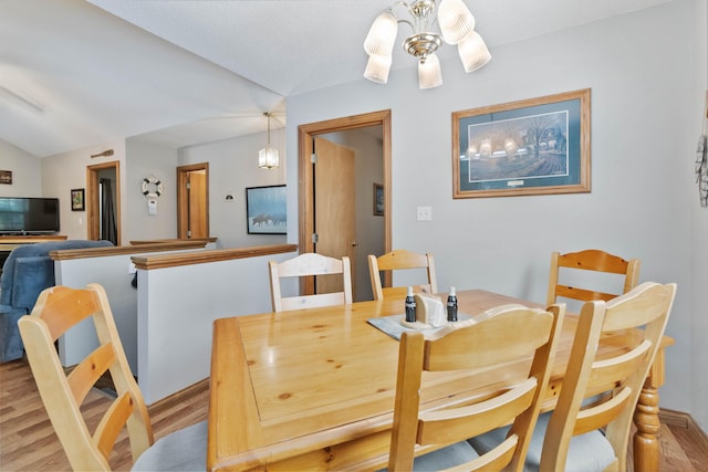 dining area featuring light wood finished floors and vaulted ceiling