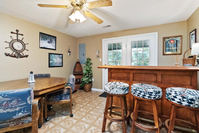 dining space featuring visible vents, electric panel, a textured ceiling, baseboards, and ceiling fan