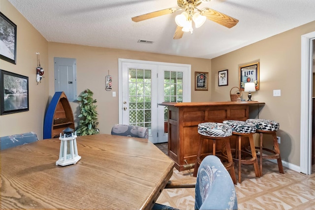 dining room with visible vents, ceiling fan, baseboards, a textured ceiling, and a bar