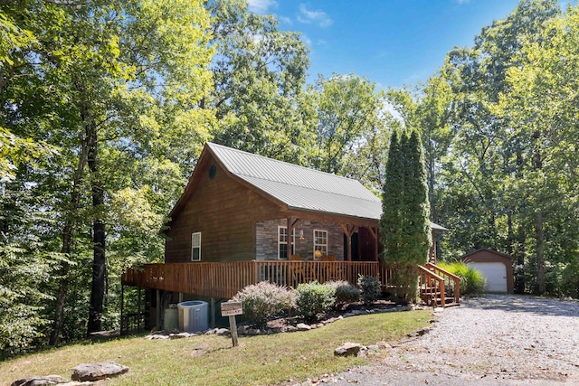 view of front of home with a garage, stone siding, a porch, an outdoor structure, and metal roof