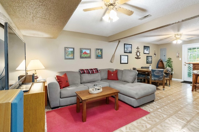 living room featuring ceiling fan, baseboards, visible vents, and a textured ceiling