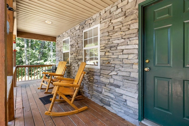 doorway to property featuring stone siding and a porch