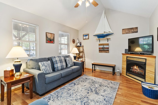 living area featuring a glass covered fireplace, a ceiling fan, light wood-type flooring, and lofted ceiling