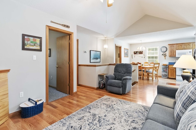 living room featuring a ceiling fan, lofted ceiling, and light wood-style floors