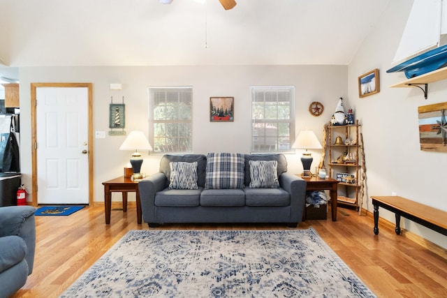 living room with light wood-style flooring, a ceiling fan, and vaulted ceiling