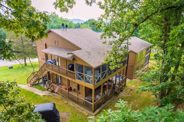 back of house featuring a lawn, roof with shingles, a wooden deck, stairs, and a patio area