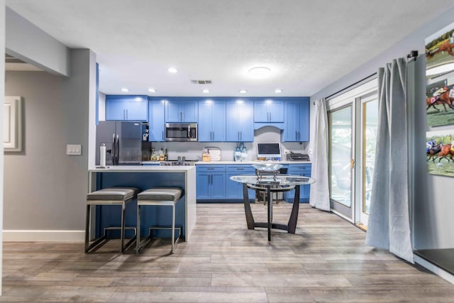 kitchen with a healthy amount of sunlight, fridge with ice dispenser, and blue cabinetry