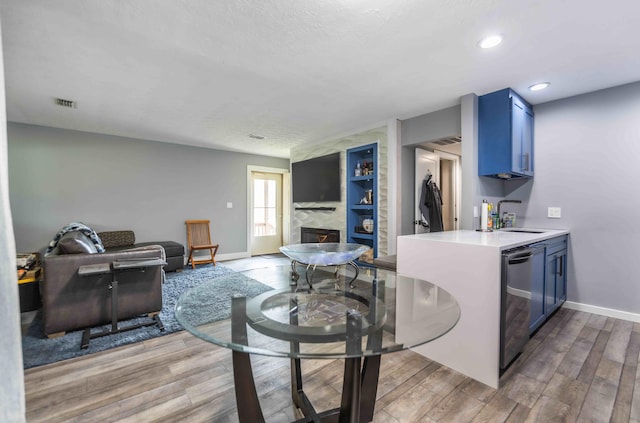 kitchen with blue cabinetry, hardwood / wood-style floors, a large fireplace, sink, and beverage cooler