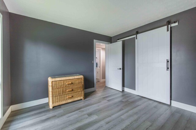 unfurnished bedroom with wood-type flooring and a barn door