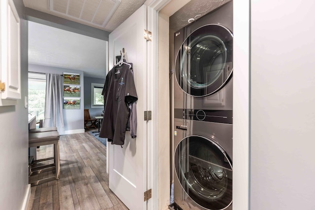 clothes washing area featuring stacked washing maching and dryer and light hardwood / wood-style flooring