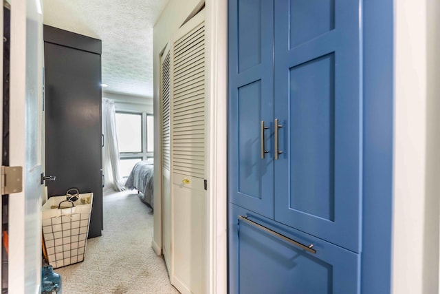 corridor with light carpet and a textured ceiling