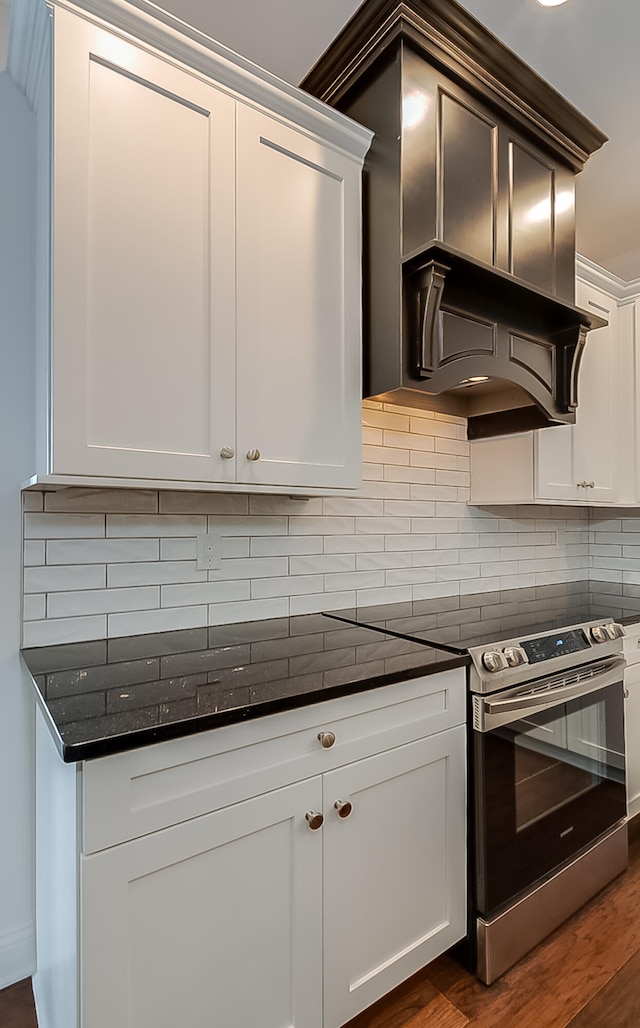 kitchen featuring white cabinetry, dark hardwood / wood-style floors, backsplash, dark stone countertops, and stainless steel electric range