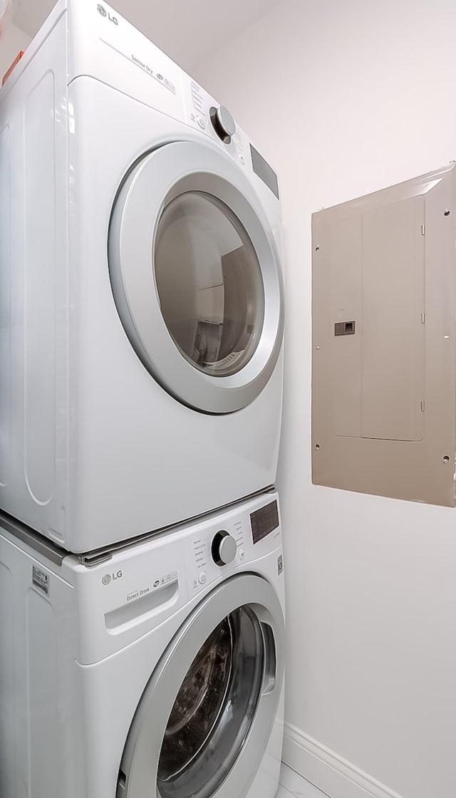 clothes washing area featuring electric panel and stacked washer / dryer