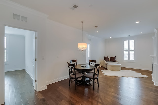 dining area featuring dark hardwood / wood-style flooring, crown molding, and a notable chandelier