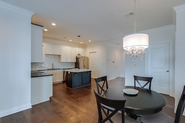 dining space featuring sink, crown molding, dark wood-type flooring, and an inviting chandelier