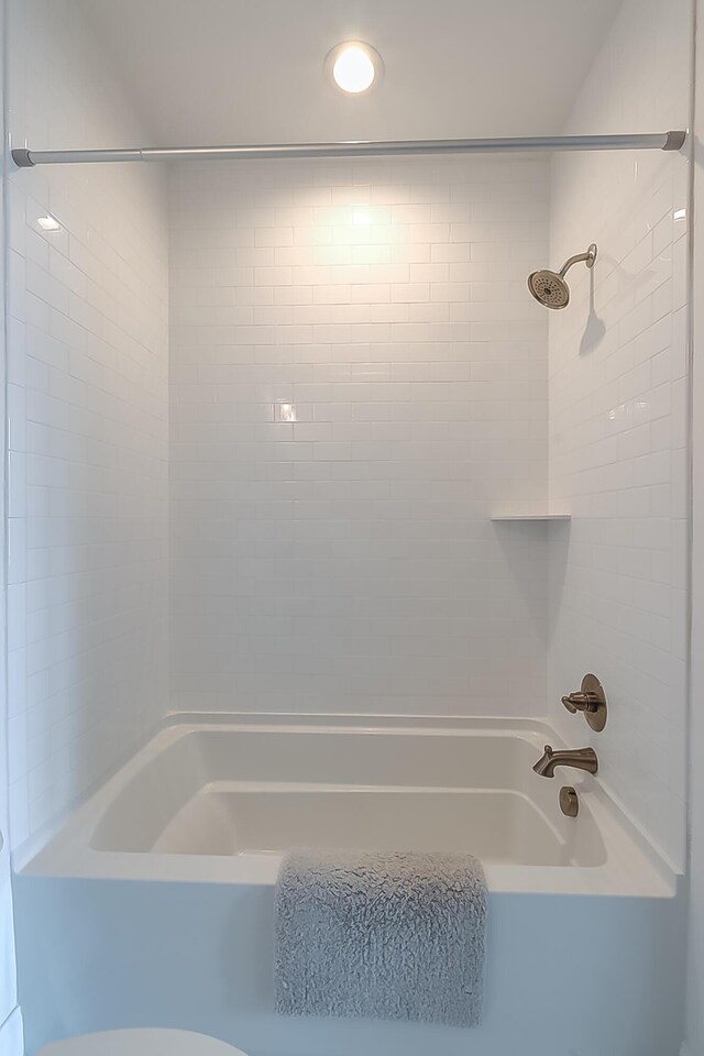 bathroom with toilet and tiled shower / bath