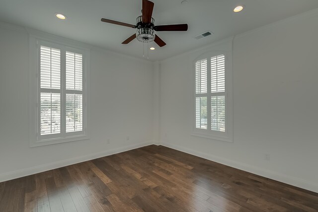 empty room featuring ceiling fan, dark wood-type flooring, and a wealth of natural light