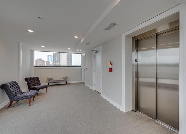 unfurnished room featuring elevator and light colored carpet