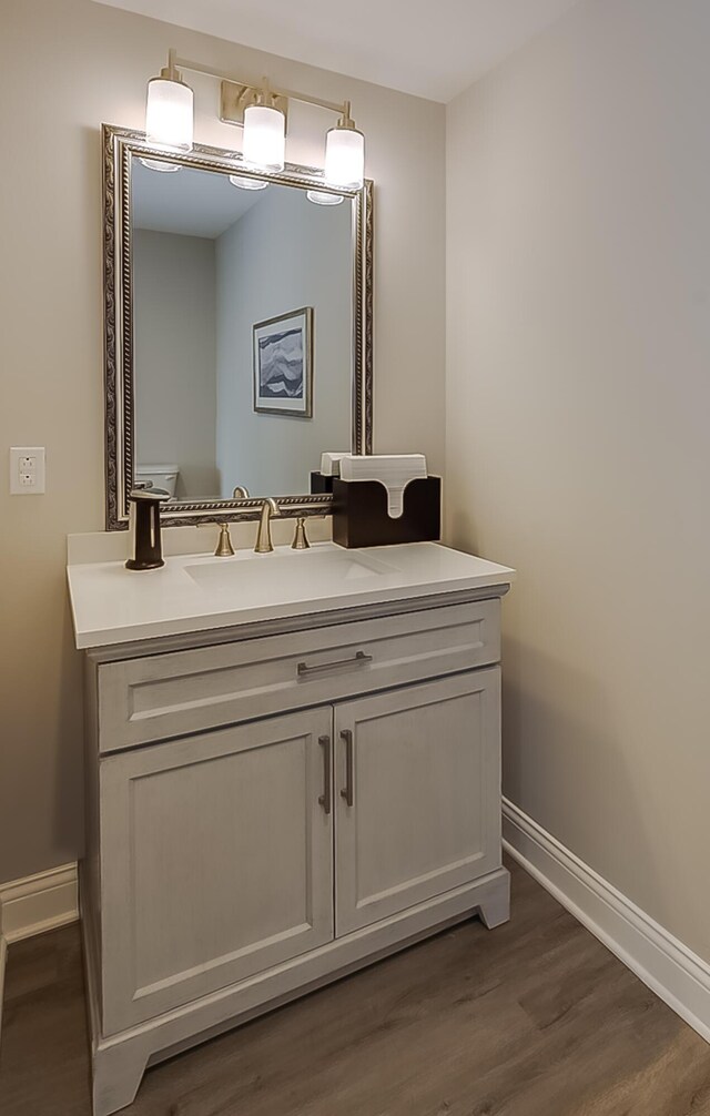 bathroom with toilet, vanity, and hardwood / wood-style flooring