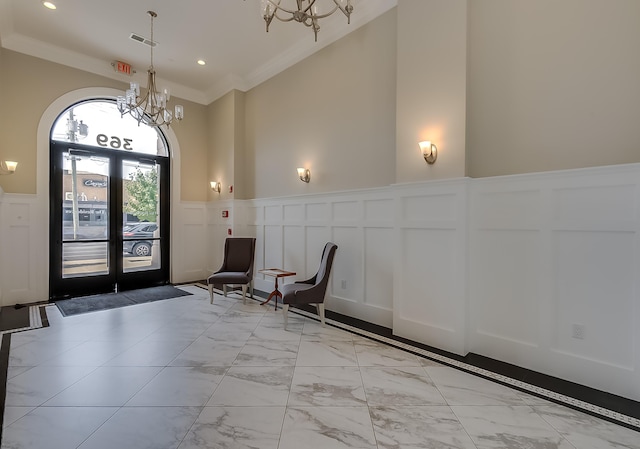 entrance foyer with crown molding, french doors, a high ceiling, and a notable chandelier