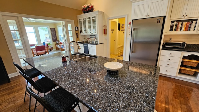 kitchen with built in fridge, dark stone countertops, dark hardwood / wood-style floors, and sink