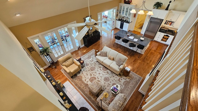 living room featuring dark wood-type flooring, ceiling fan, and a towering ceiling