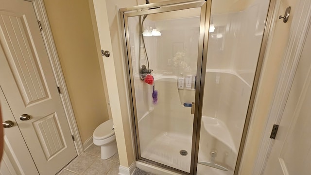 bathroom with tile patterned flooring, toilet, and an enclosed shower