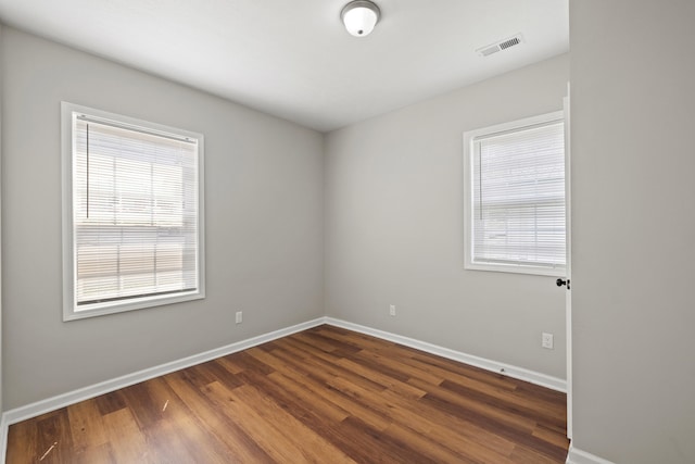 empty room featuring a healthy amount of sunlight and dark hardwood / wood-style floors