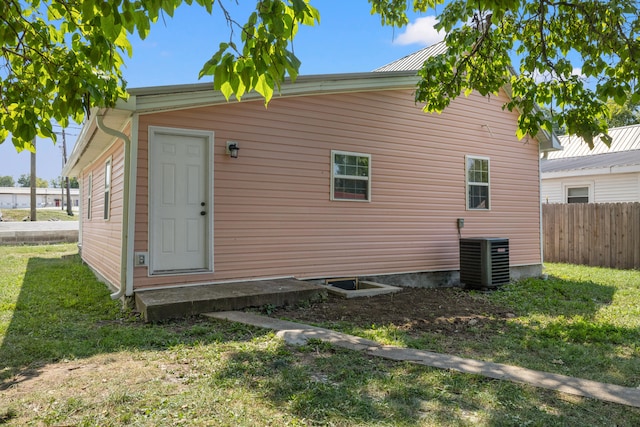 rear view of property featuring central AC unit and a lawn