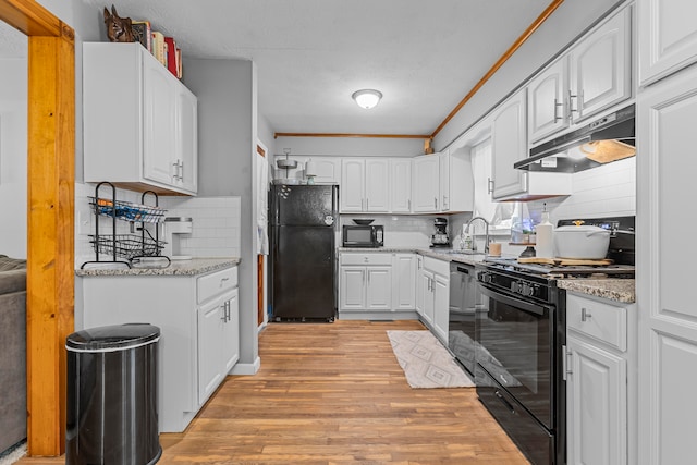 kitchen featuring black appliances, light stone countertops, and white cabinetry