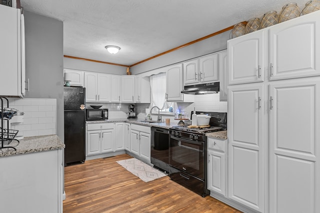 kitchen with black appliances, backsplash, light hardwood / wood-style floors, sink, and white cabinetry