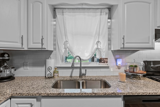 kitchen with white cabinets, light stone countertops, backsplash, and sink