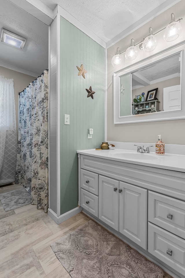 bathroom with curtained shower, crown molding, a textured ceiling, and vanity