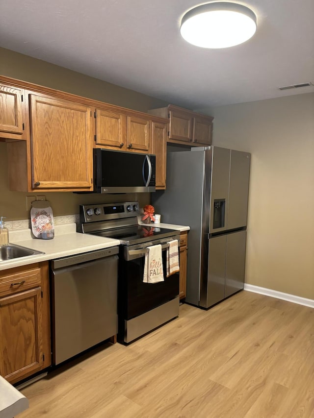 kitchen featuring baseboards, light wood finished floors, visible vents, light countertops, and appliances with stainless steel finishes