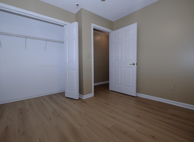 unfurnished bedroom featuring a closet, baseboards, and light wood-style floors