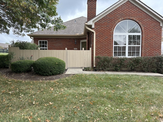 view of property exterior featuring a yard, fence, brick siding, and a chimney