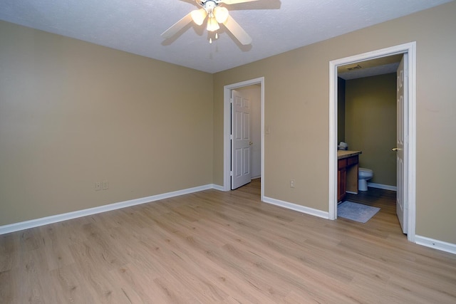 unfurnished bedroom featuring light wood finished floors, visible vents, ensuite bathroom, and baseboards