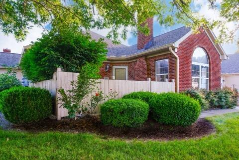 view of side of home with brick siding, a chimney, and fence