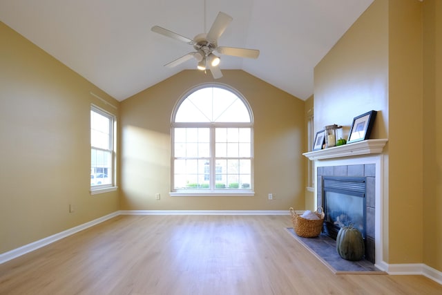 unfurnished living room with a healthy amount of sunlight, a tile fireplace, light wood-type flooring, and lofted ceiling