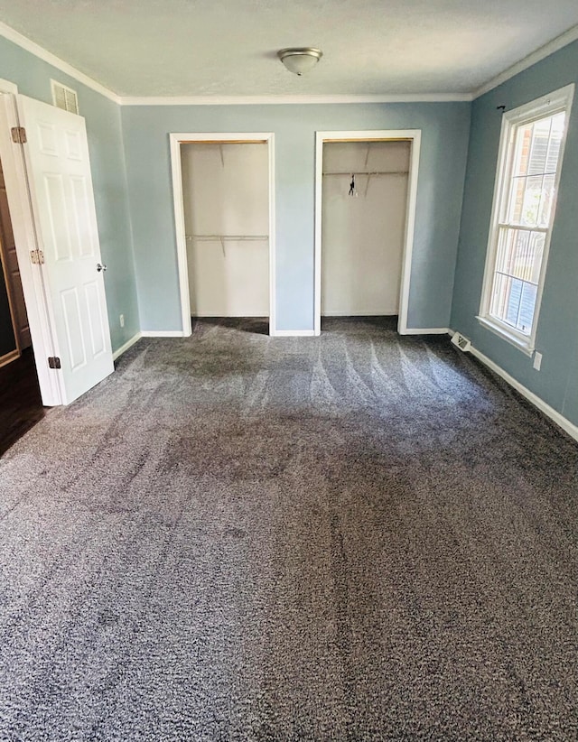 unfurnished bedroom with two closets, ornamental molding, and carpet floors